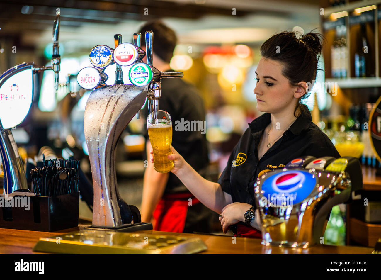 Un travail de barmaid versant une pinte de bière blonde dans un pub bar UK Banque D'Images