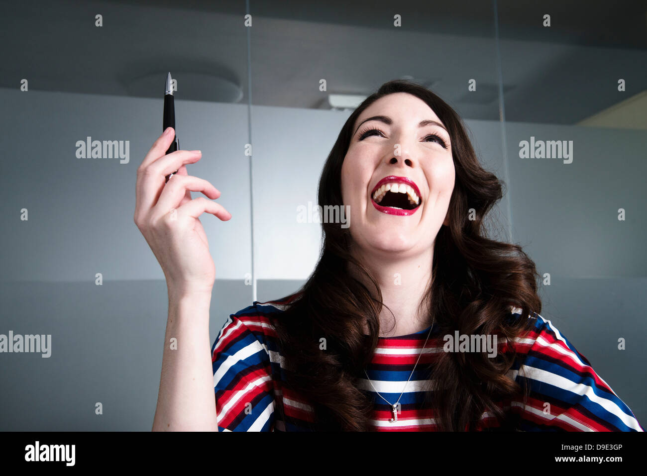 Femme avec tête rejetée en arrière en riant follement dans l'environnement de bureau Banque D'Images