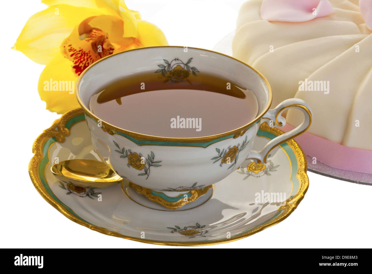 Meubles anciens tasse pleine de thé avec gâteau et orchidée dorée en arrière-plan isolé sur blanc. Banque D'Images