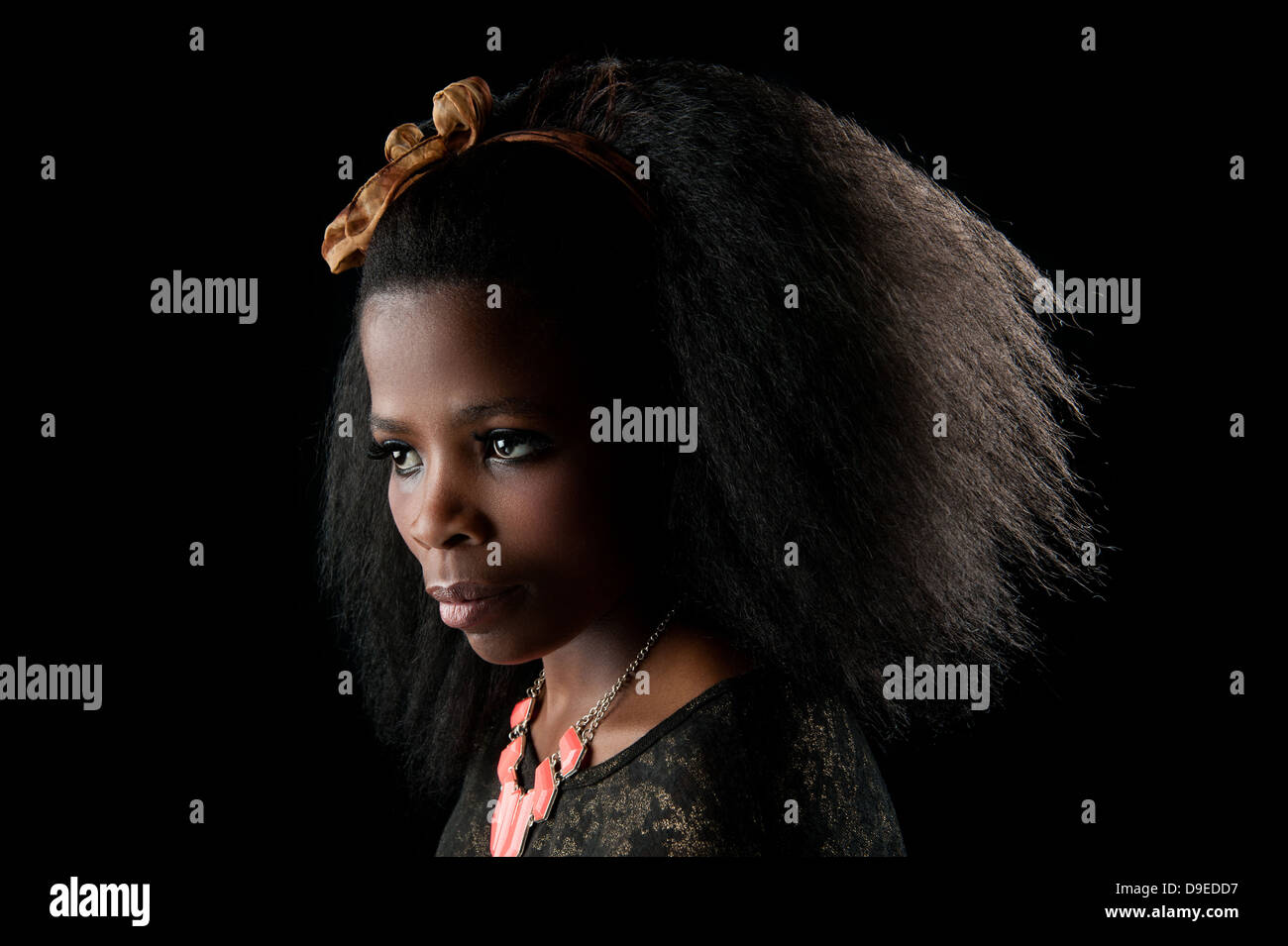 Jeune femme africaine avec de beaux cheveux afro, une clé faible background studio shot. L'expression faciale spectaculaire. Une belle peau douce. Banque D'Images