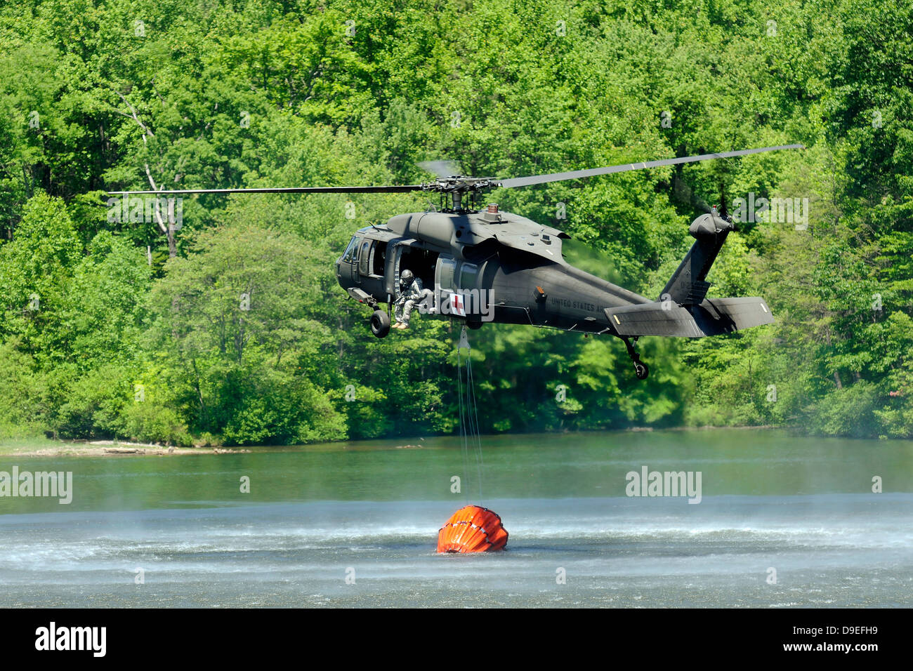 Un hélicoptère Blackhawk UH-60 remplit un seau d'eau en suspension dans le lac Marquette, Michigan. Banque D'Images