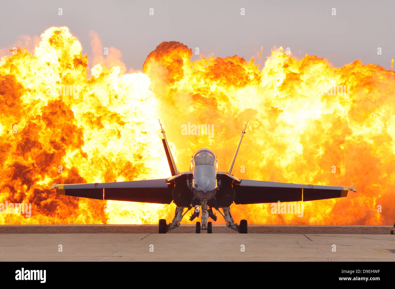 Un F/A-18 Hornet est situé sur l'axe de vol comme un mur de feu explose derrière elle. Banque D'Images