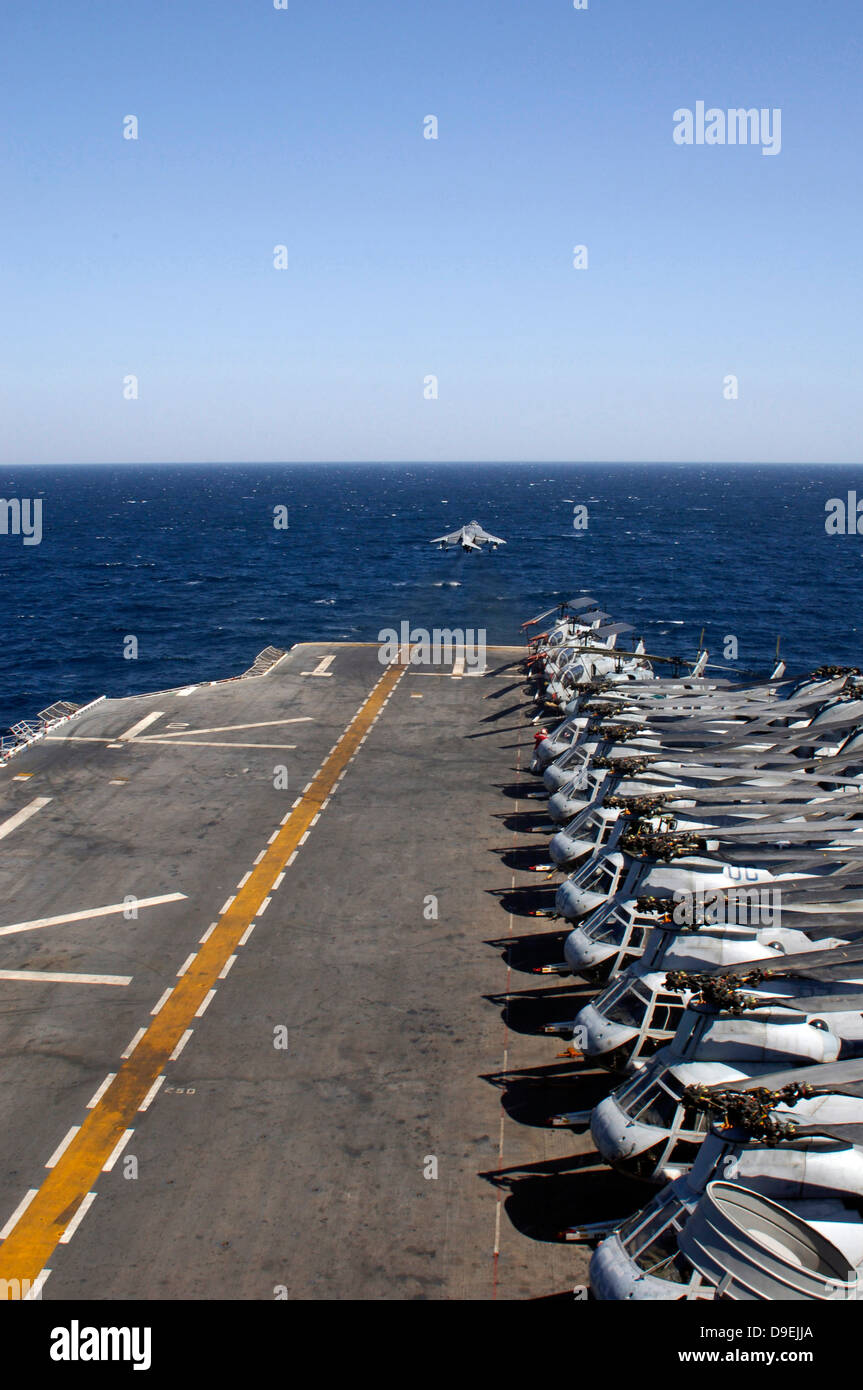 Une entrée AV-8B décolle de l'envol du USS Tarawa bordée d'hélicoptères. Banque D'Images