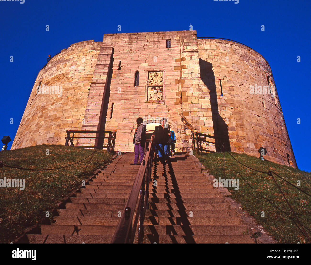 Clifford's Tower - monument historique et une attraction touristique, contre un ciel bleu clair, avec des visiteurs walking down steps, York, Yorkshire, Angleterre, Royaume-Uni. Banque D'Images