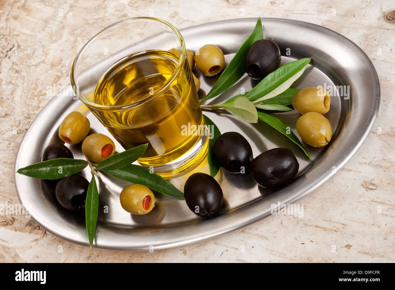Le verre avec de l'huile d'olive et d'olives sur un plateau en verre, avec de l'huile d'olive et d'olive sur une plus platement Banque D'Images