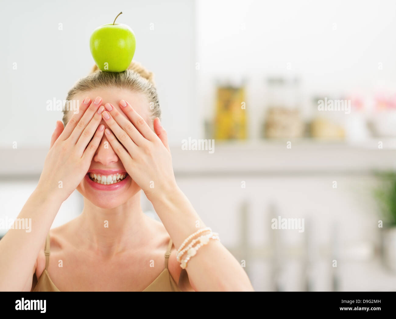 Teenage girl avec Apple sur la tête fermer les yeux avec les mains Banque D'Images