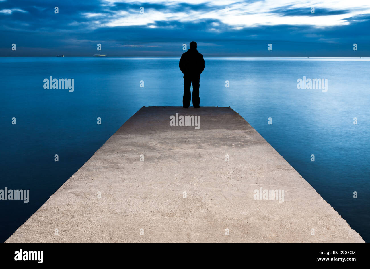 L'homme est debout sur une jetée à la coucher du soleil Banque D'Images L'homme est debout sur une jetée à la coucher du soleil Banque D'Images