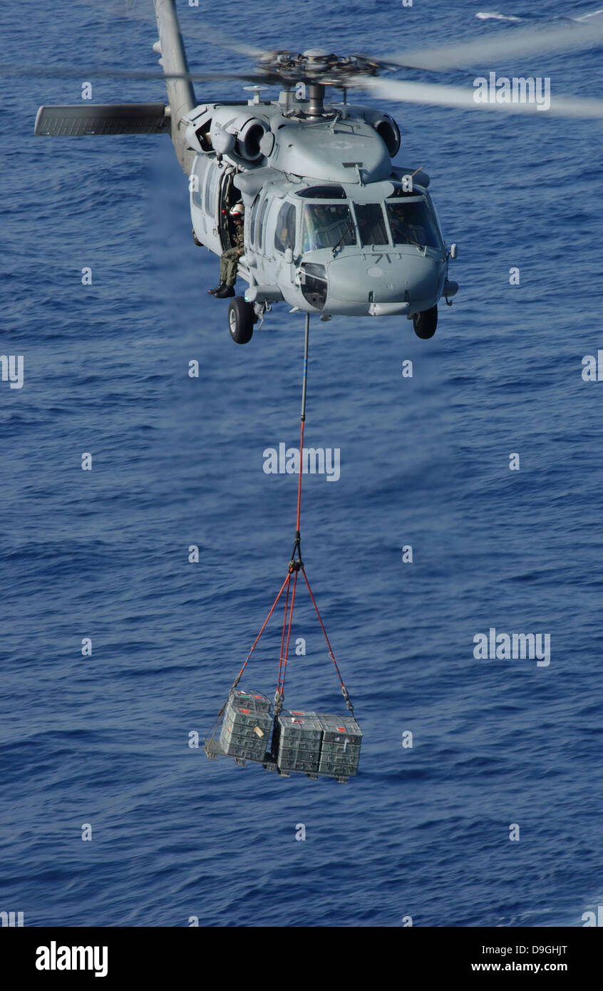 Un MH-60S Knighthawk fournitures transports au cours d'un ravitaillement en mer Banque D'Images