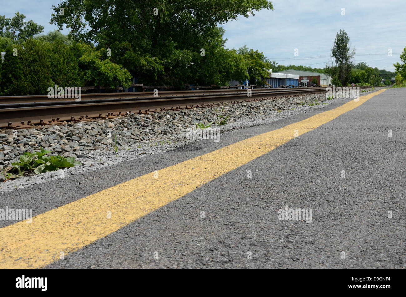 Voie ferrée avec parking auto près de l'intersection de la route. Banque D'Images