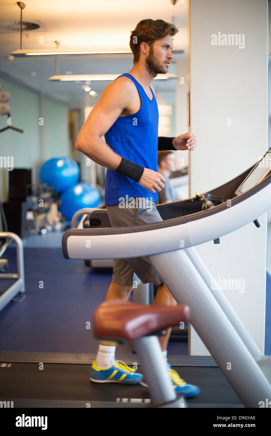 Homme qui court sur un tapis roulant dans une salle de sport Banque D'Images