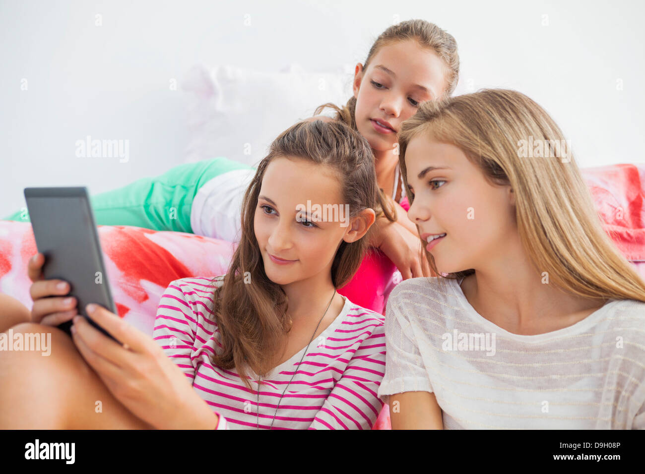 Trois jeunes filles à l'aide d'une tablette numérique à un pyjama Banque D'Images