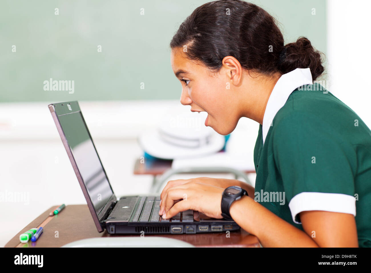 Surpris middle school girl looking at her laptop in classroom Banque D'Images