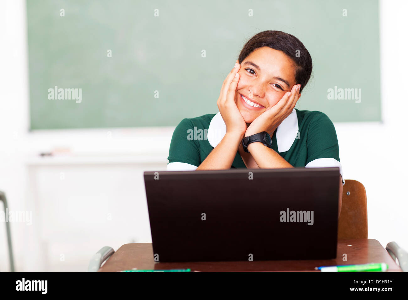 Portrait of smiling teen middle school girl using computer in classroom Banque D'Images