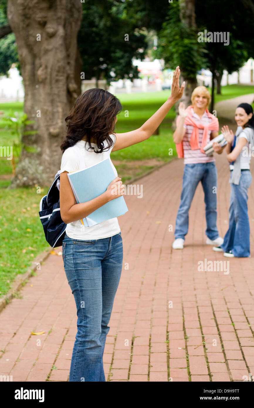 Female college student agitant au revoir à des amis Banque D'Images