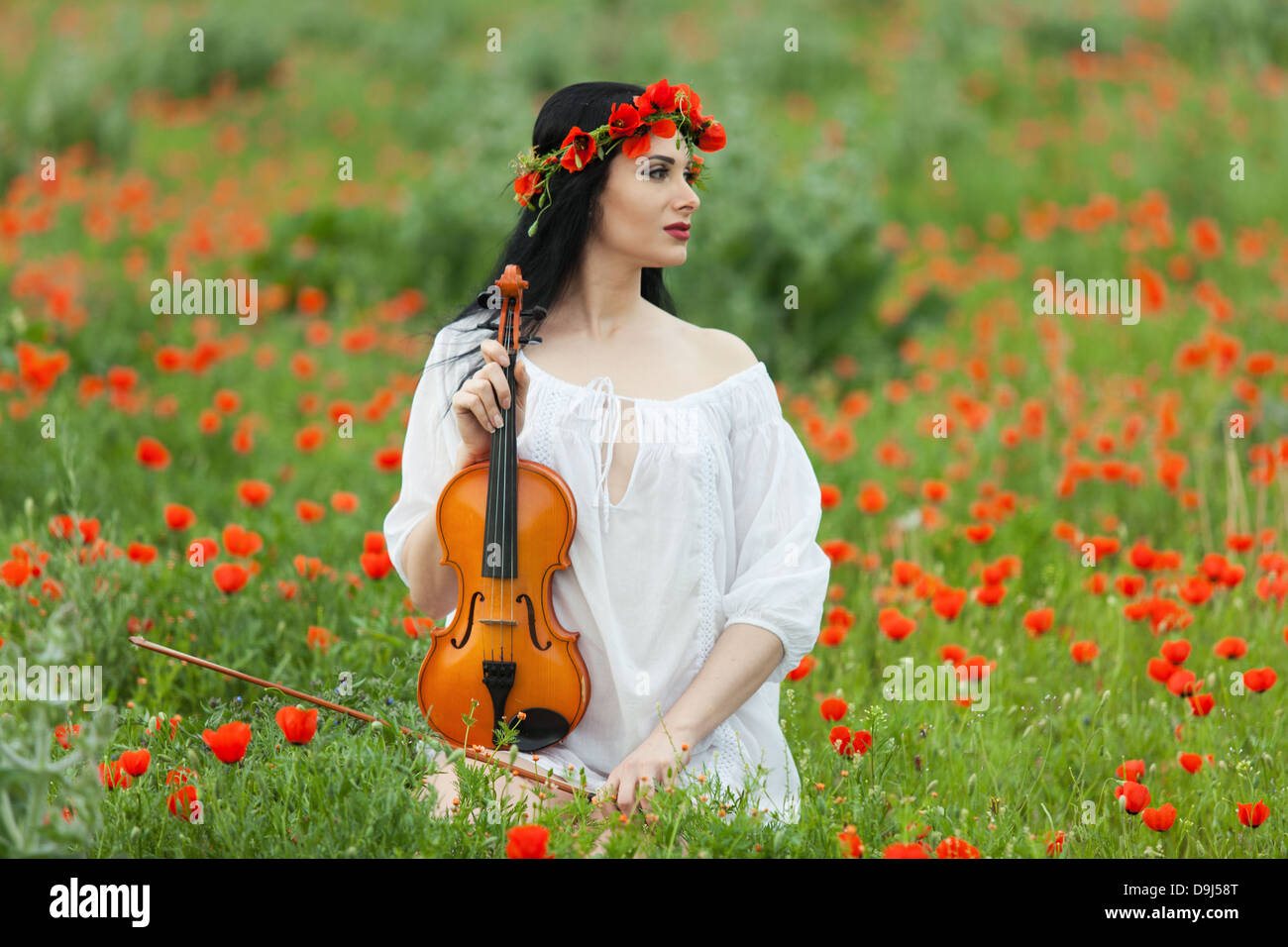 Une fille avec un violon dans une chemise blanche sur un champ de coquelicots Banque D'Images