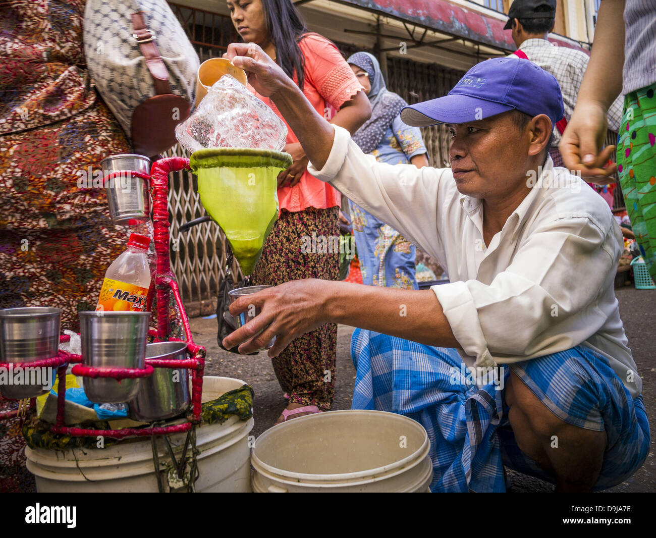 16 juin 2013 - Yangon, Myanmar - un vendeur d'eau dans la région de Yangon.  Il remplit des bouteilles d'eau en plastique par l'eau du robinet sur un  bloc de glace. Yangon,