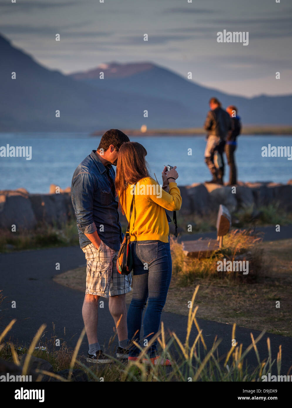 Couple à prendre des photos du soleil de minuit, Seltjarnarnes ville, banlieue de Reykjavik, Islande Banque D'Images