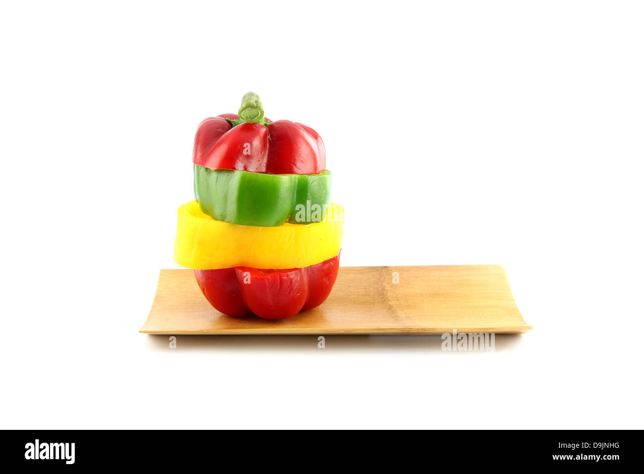 Couper les trois couleur de poivron dans disposés verticalement sur un plat en bambou. Banque D'Images