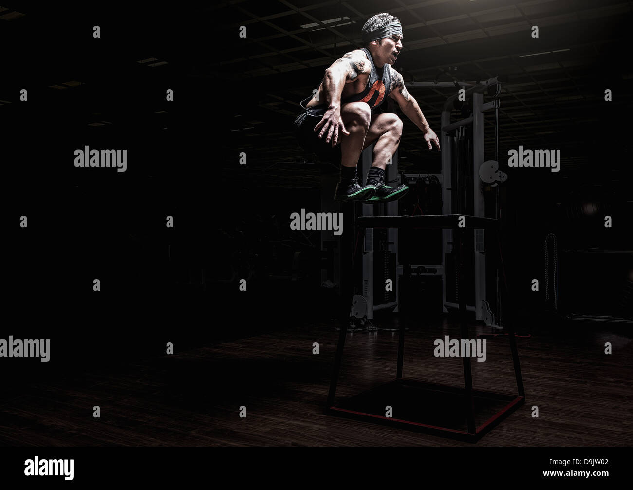 Jeune homme sautant in gym Banque D'Images