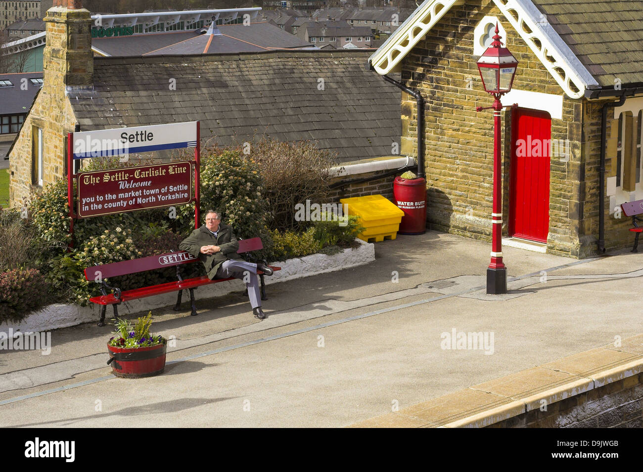 Homme assis sur un banc sur la plate-forme à Settle railway station Banque D'Images