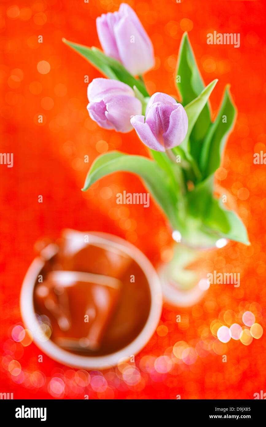 Tulip fleurs de printemps avec les tasses de café sur red sparkle background, super shallow dof Banque D'Images