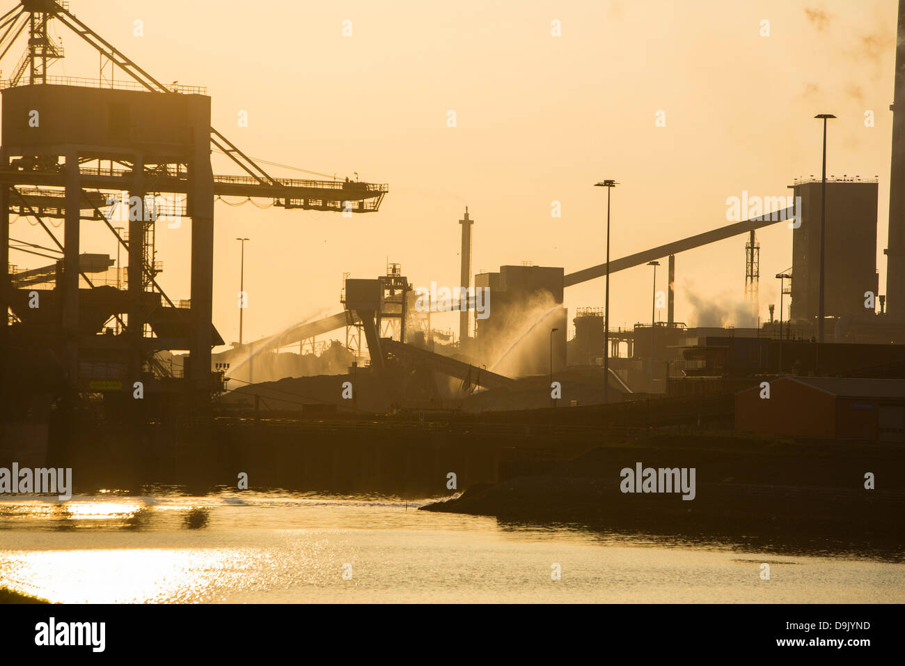 Le charbon importé de grues à la Tata Steel works à Ijmuiden Pays-bas, au coucher du soleil. Banque D'Images