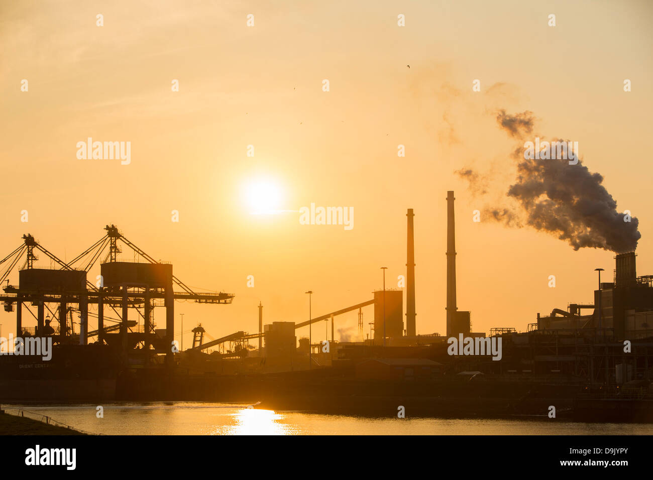 Le charbon importé de grues à la Tata Steel works à Ijmuiden Pays-bas, au coucher du soleil. Banque D'Images