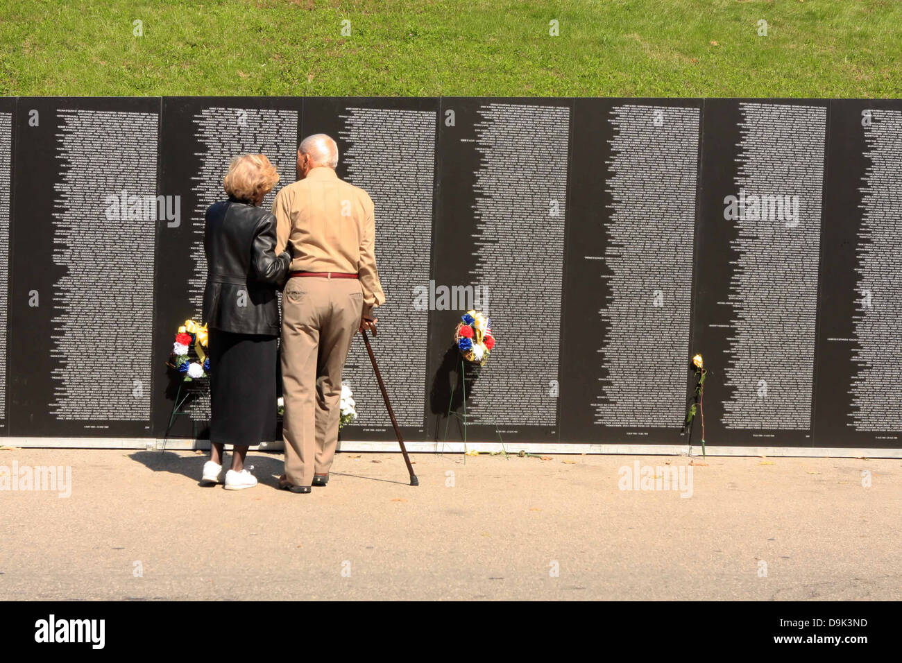 Couple de personnes à la recherche à la guerre du Vietnam voyage Memorial Wall homme femme fleurs de canne Banque D'Images