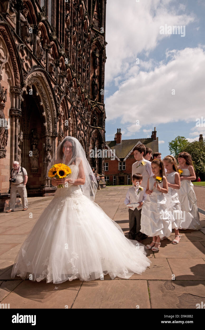 Mariée en robe de mariée blanche à l'avant de l'ouest de la cathédrale de Lichfield St Tchad avec pages et les filles de fleurs Banque D'Images