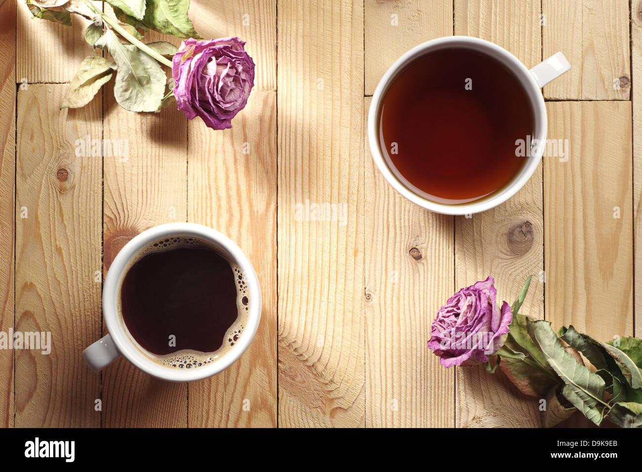 Tasse de café, thé et deux roses séchées sur une table en bois Banque D'Images