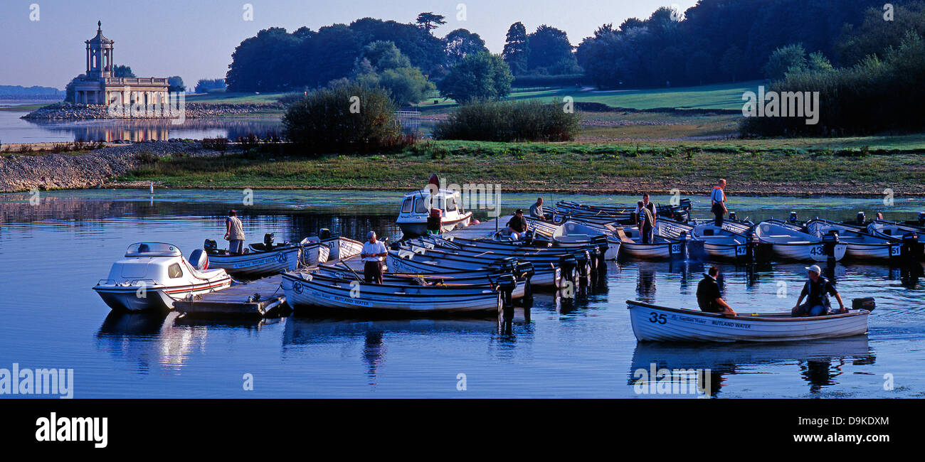 Pêcheur dans la préparation de leurs bateaux pour un voyage de pêche, sur Rutland Water, Angleterre, Royaume-Uni, avec l'Église Normanton dans l'arrière-plan. Banque D'Images