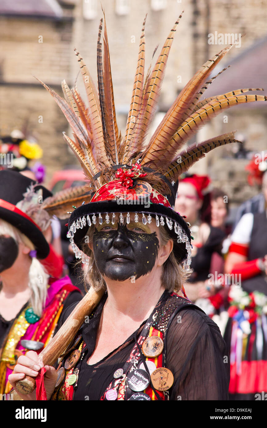 Femme Morris dancer avec la face noire et plumes dans son chapeau à Skipton, Yorkshire du Nord, Angleterre Banque D'Images