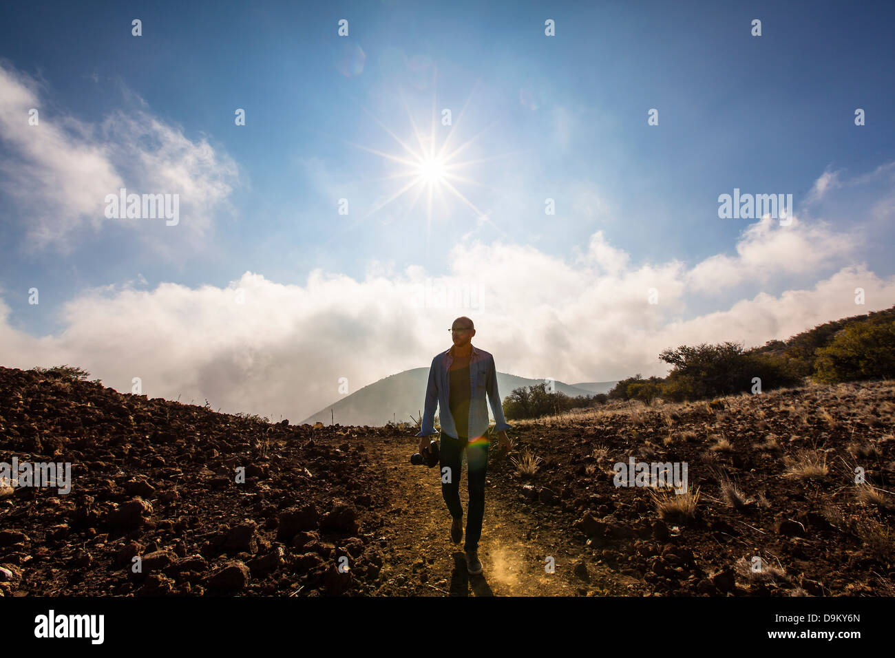 Mid adult man holding camera dans paysage ensoleillé Banque D'Images