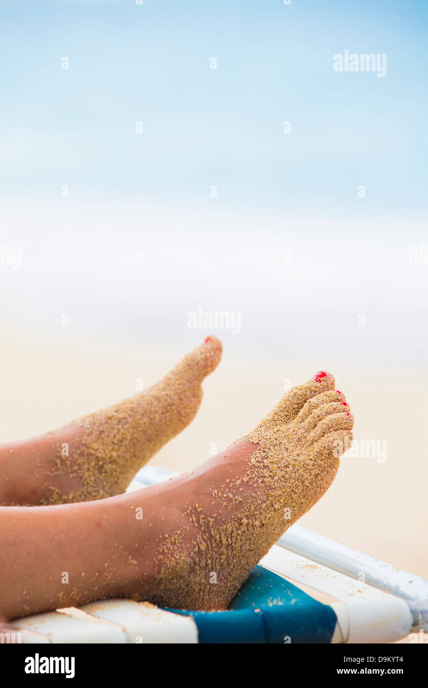 Pieds de femme couverte de sable sur une chaise longue Photo Stock - Alamy