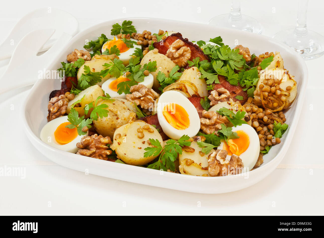 La Salade de pommes de terre avec des oeufs et de lentilles - Salade de pommes de terre tiède avec l'oeuf, les lentilles, le persil, Lardons, Noix, oignon caramélisé et à la moutarde. Banque D'Images