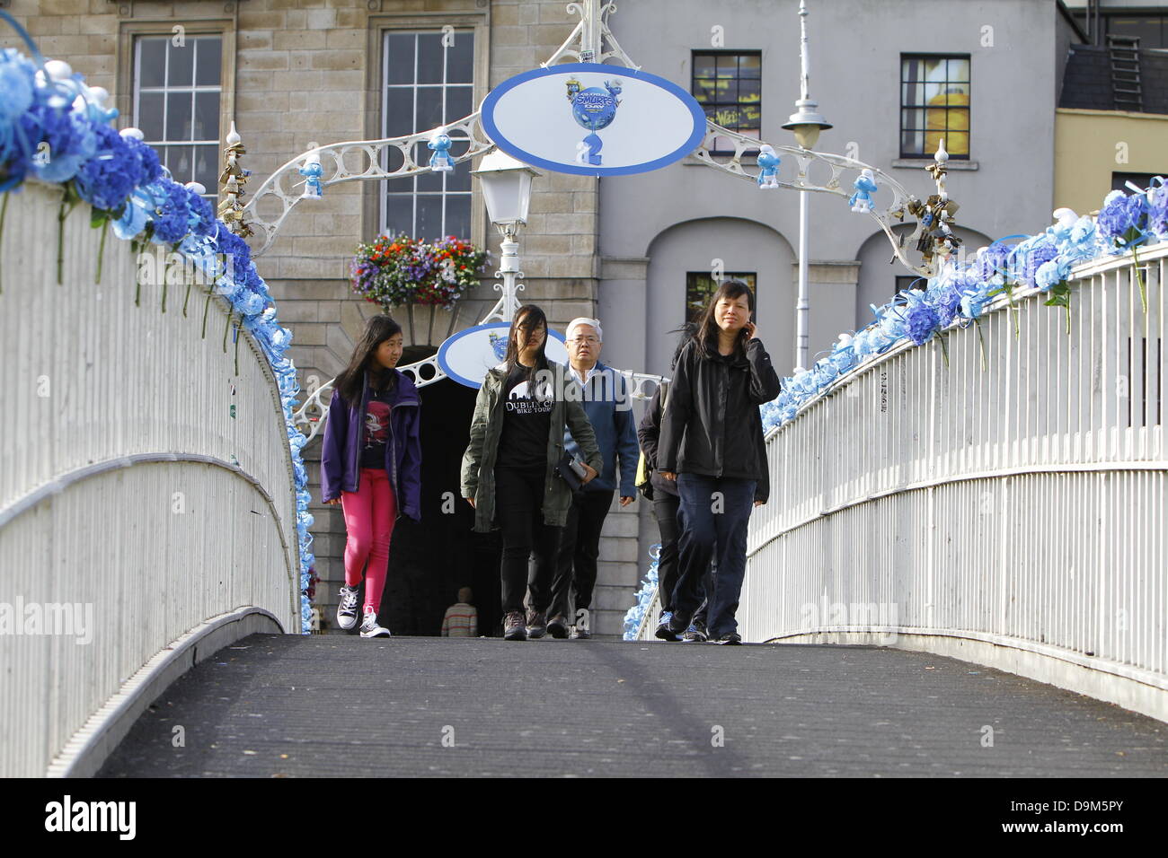 Dublin, Irlande. 22 juin 2013. Les touristes à pied sur le Ha'penny Bridge, qui est décoré avec des fleurs bleues et peu de figurines Schtroumpf Schtroumpfs mondial 24. Acteurs habillés comme le Grand Schtroumpf et Schtroumpfette posés à la Dublin's Ha'penny Bridge dans une promotion pour le prochain "Les Schtroumpfs 2" film. La photo téléphonique a eu lieu sur les Schtroumpfs, jour qui est célébrée autour de l'anniversaire du créateur des Schtroumpfs Payo. Crédit : Michael Debets/Alamy Live News Banque D'Images
