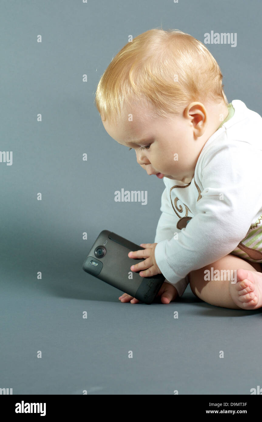 Blond bébé jouant avec smart phone Banque D'Images