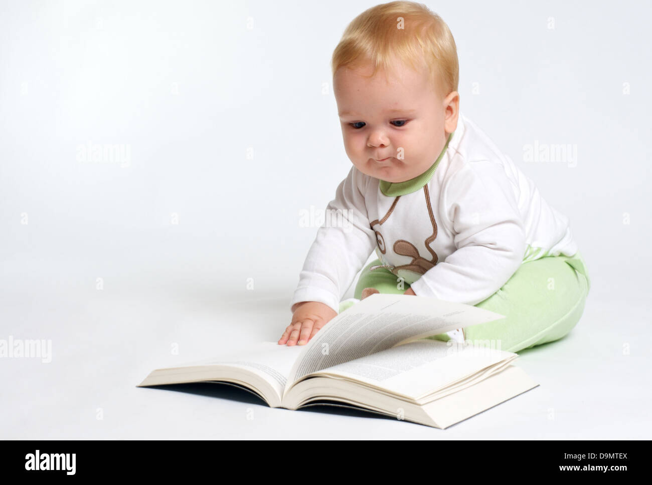 Baby-sitting blonde intelligente et la lecture d'un livre Banque D'Images