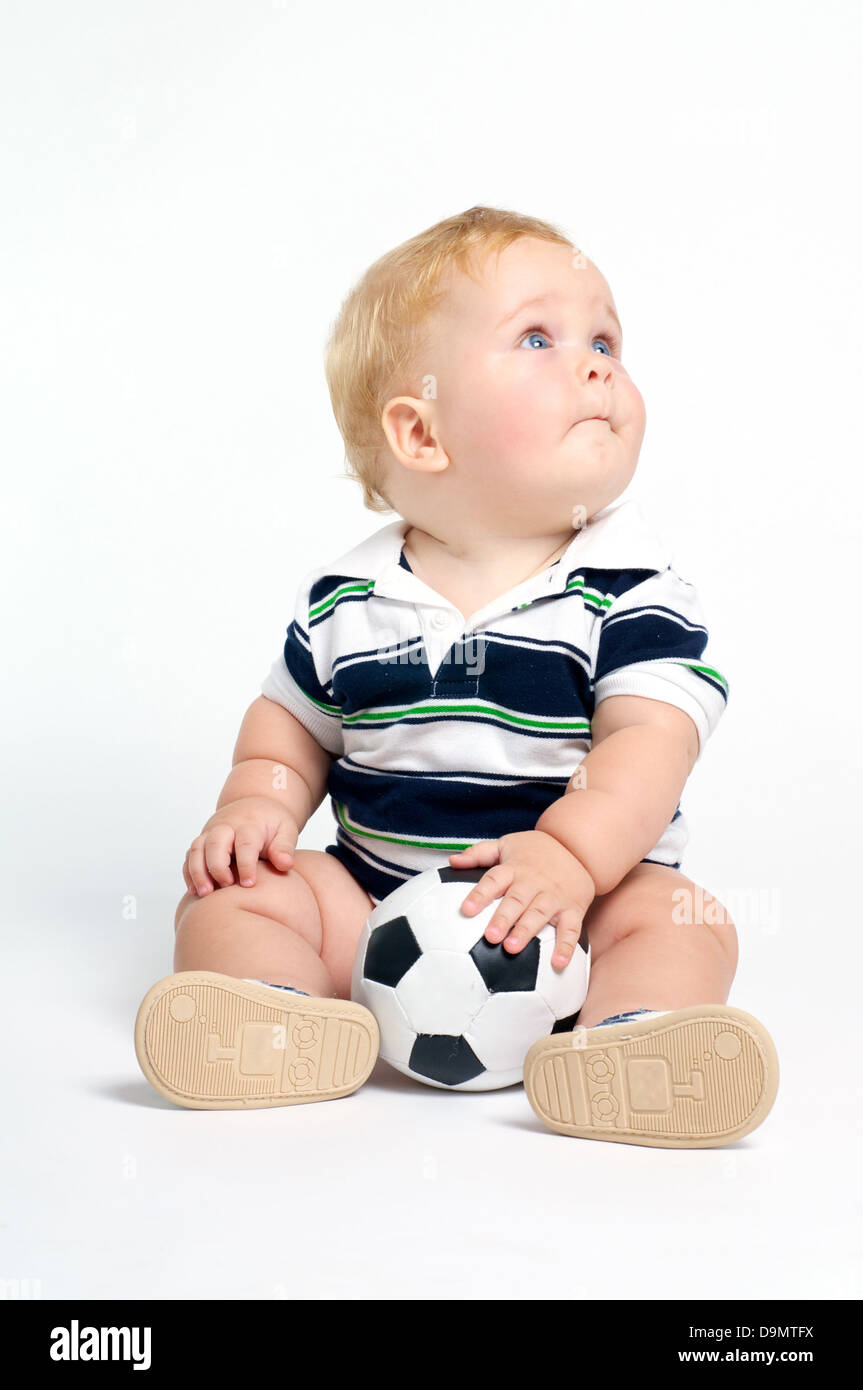 Fun bébé blond aux yeux bleus, jouant avec un ballon de football Banque D'Images