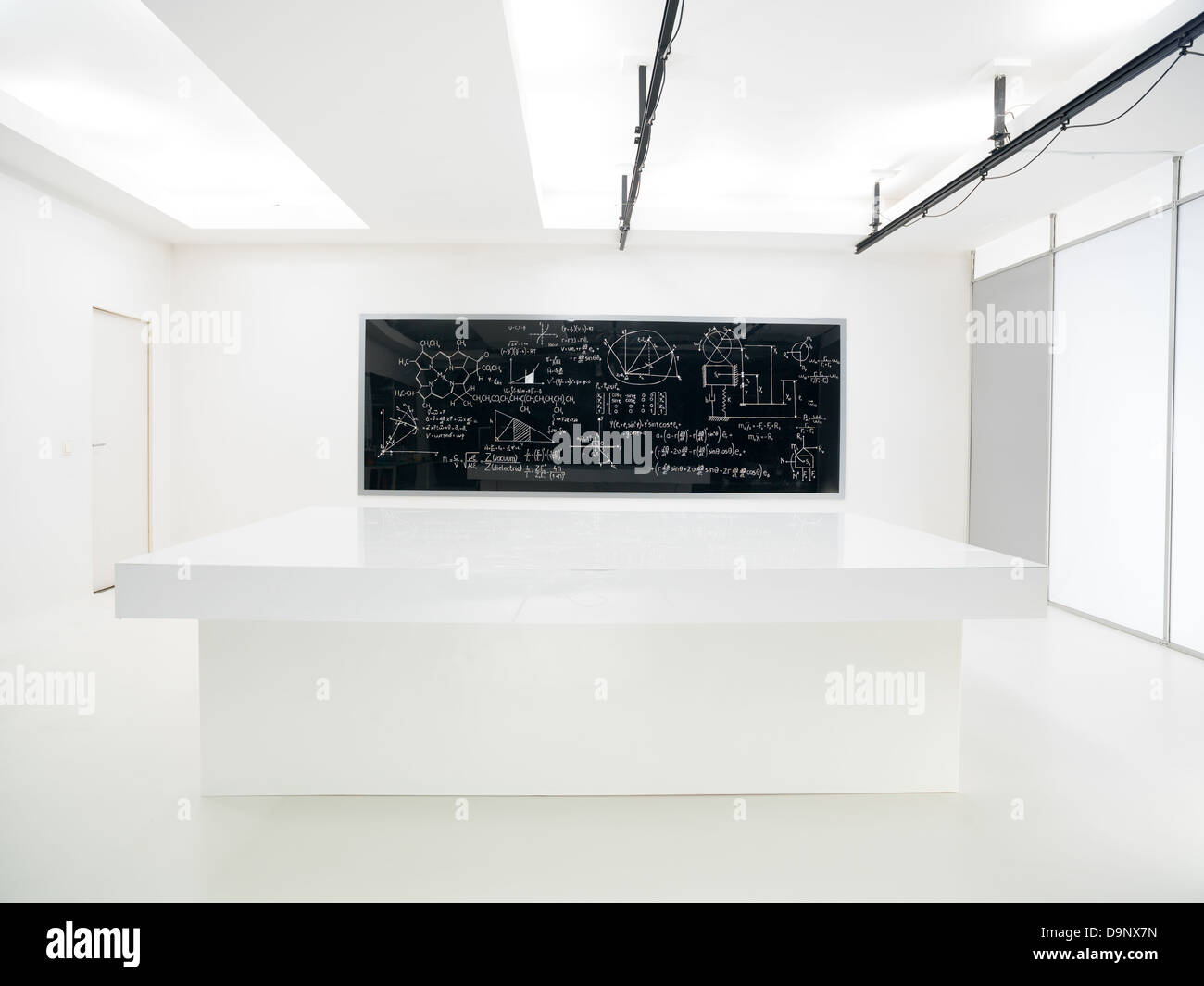 Vue générale d'un laboratoire de chimie avec une table de travail et tableau noir avec des formules sur-le sur l'arrière-plan Banque D'Images