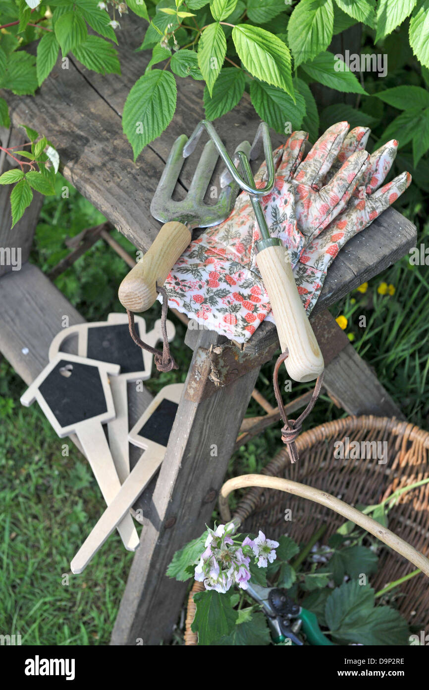 Outils de jardinage et panier avec fleurs dans jardin Banque D'Images