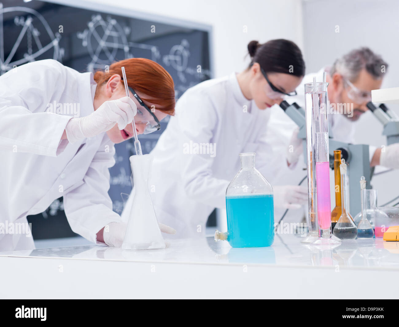 Close-up de trois personnes dans un laboratoire de chimie effectuant des  expriences chimiques sur une table de labo avec lab outils et liquides  colors Photo Stock - Alamy