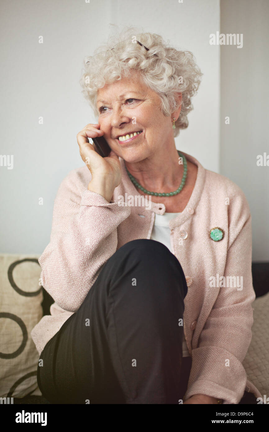 Happy senior femme avec un téléphone cellulaire à la maison Banque D'Images