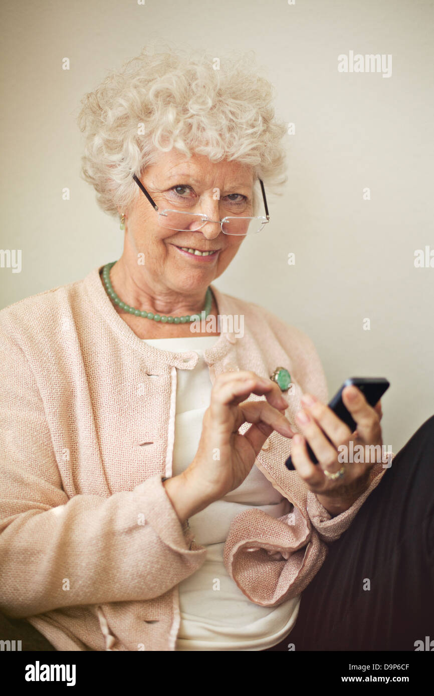Vieille dame texting quelqu'un en utilisant son téléphone portable Banque D'Images
