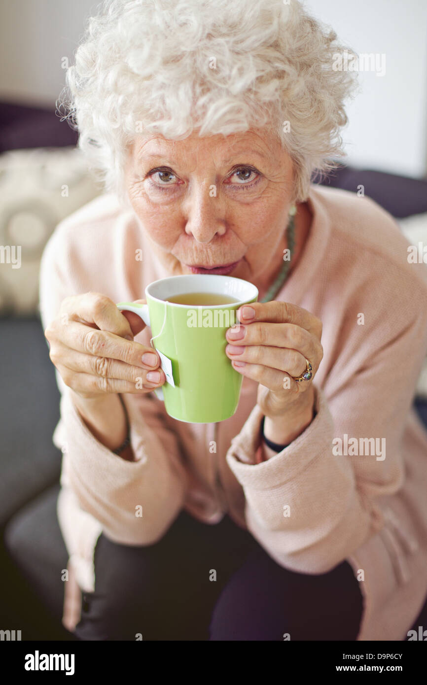 Libre d'une dame d'âge mûr qui vous regarde en buvant son thé Banque D'Images