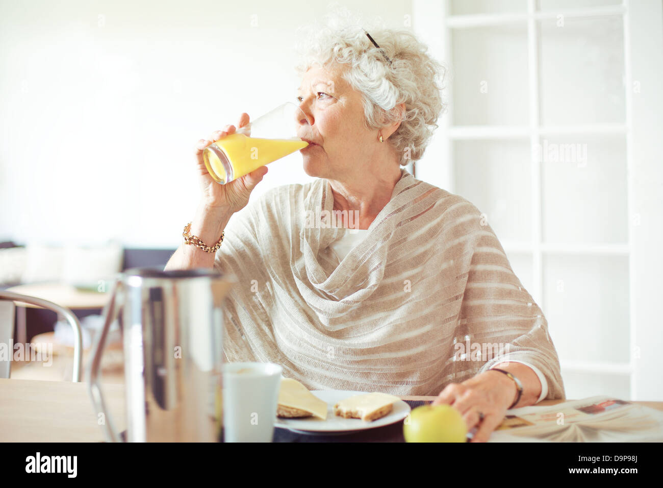 Femme âgée de boire un verre de jus d'orange Banque D'Images