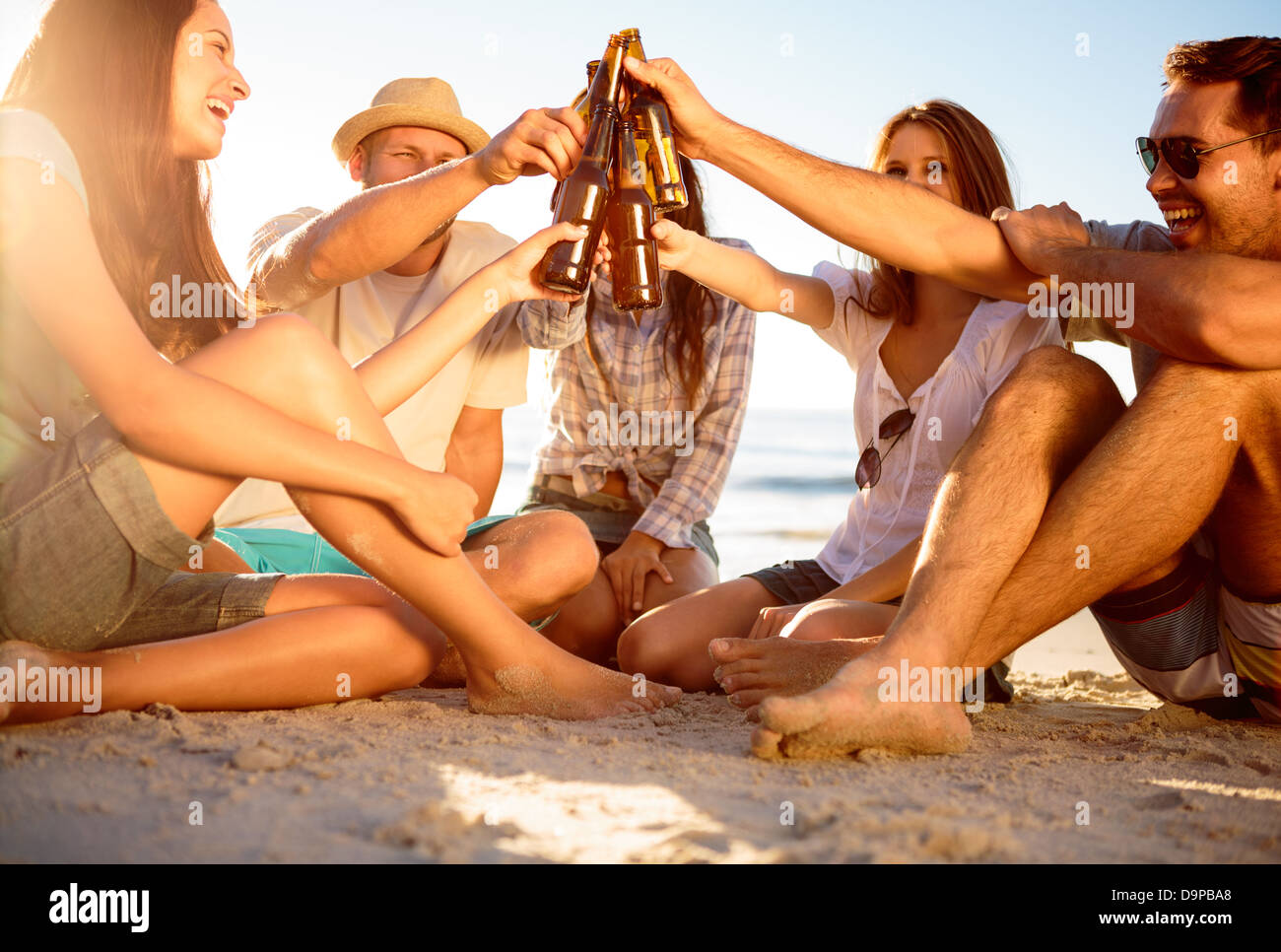 Les Amis en cliquant sur leurs bouteilles de bière sur la plage Banque D'Images