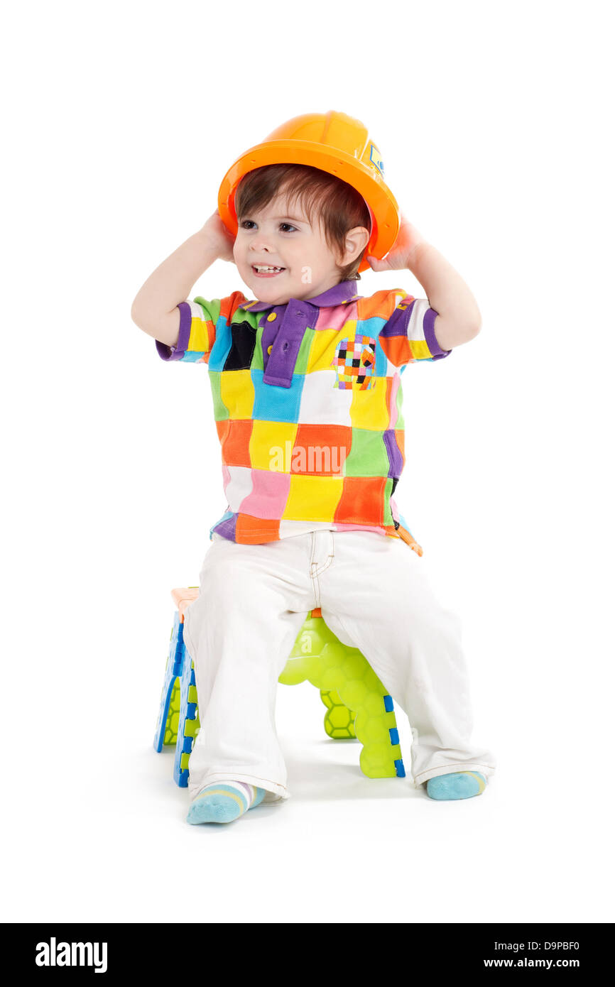 Mignon bébé enfant assis avec casque de construction Banque D'Images
