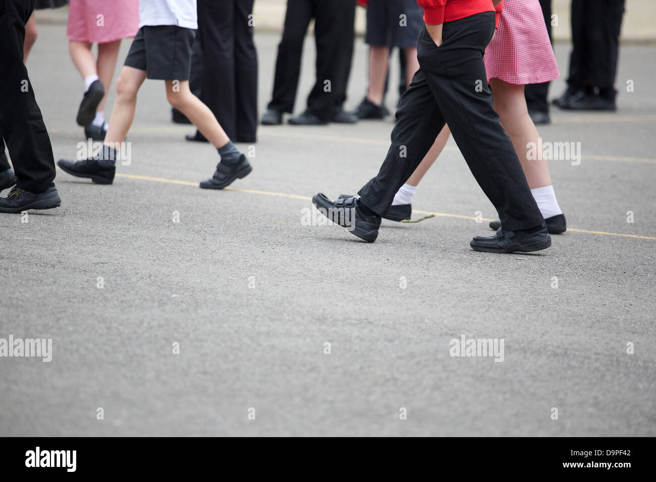 Les enfants des écoles primaires au Royaume-Uni à la pause de récréation sur l'aire de jeu montrant les jambes seulement Banque D'Images