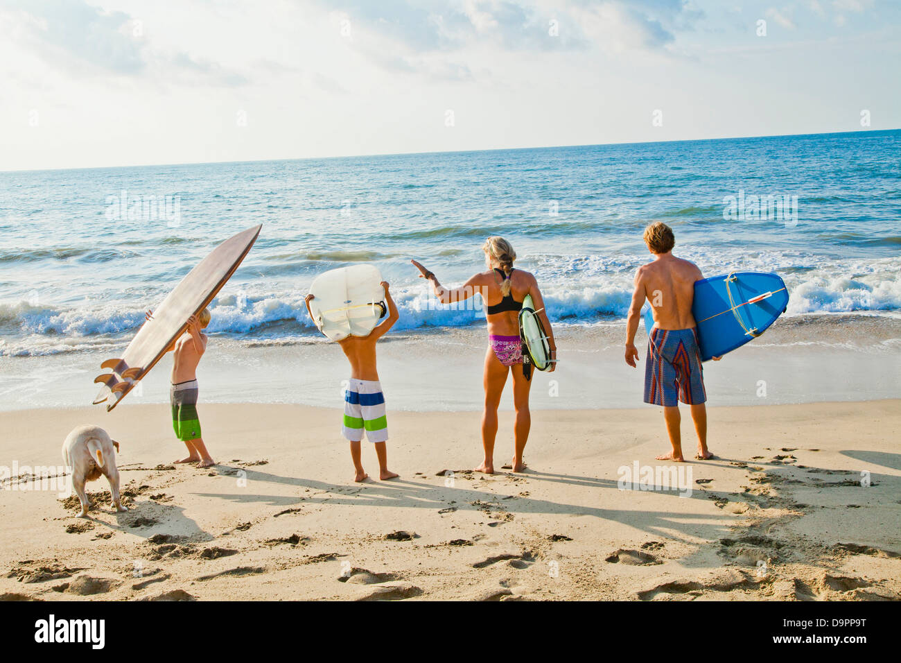 Family on beach holding surfboards Banque D'Images
